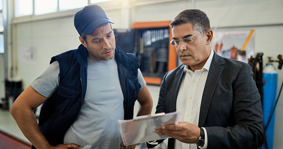 dois homens em pé conversando sobre a gestão de manutenção da sua empresa