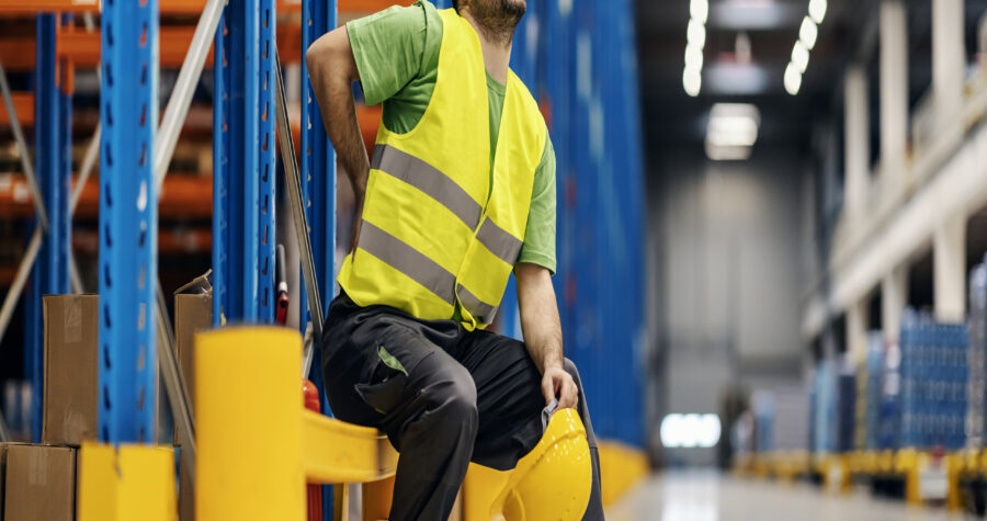 A storage worker in pain having back pain and massage the painful place.